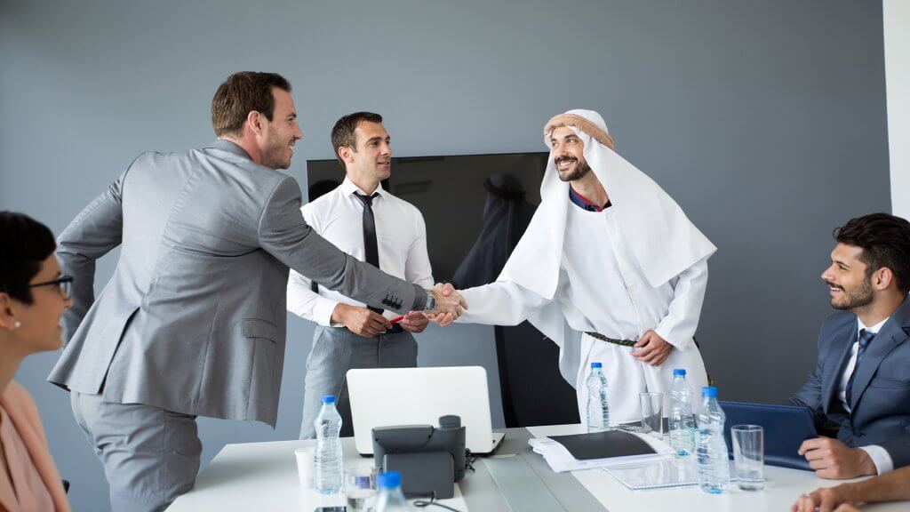 Businessmen from different backgrounds ending a successful meeting with a handshake
