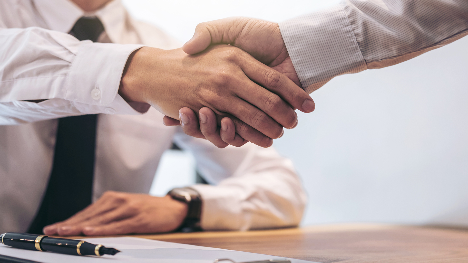 Estate broker agent and customer shaking hands after signing contract documents